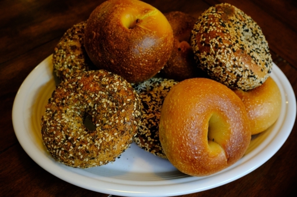 a picture of a white oval plate with different kinds of bagels stacked on it. 