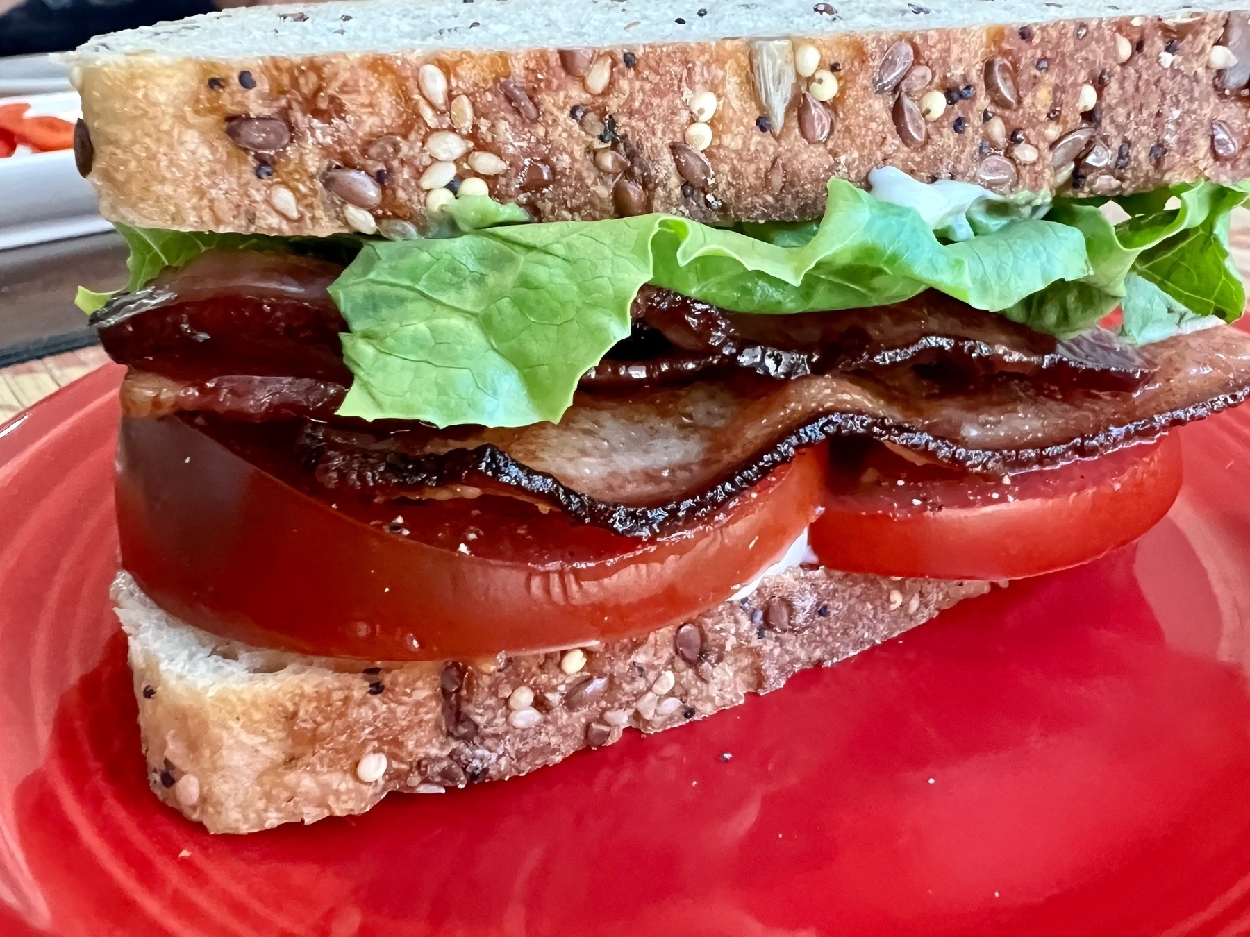 close up virw of a bacon, lettuve, tomato, and avocado sandwich on seeded bread. 
